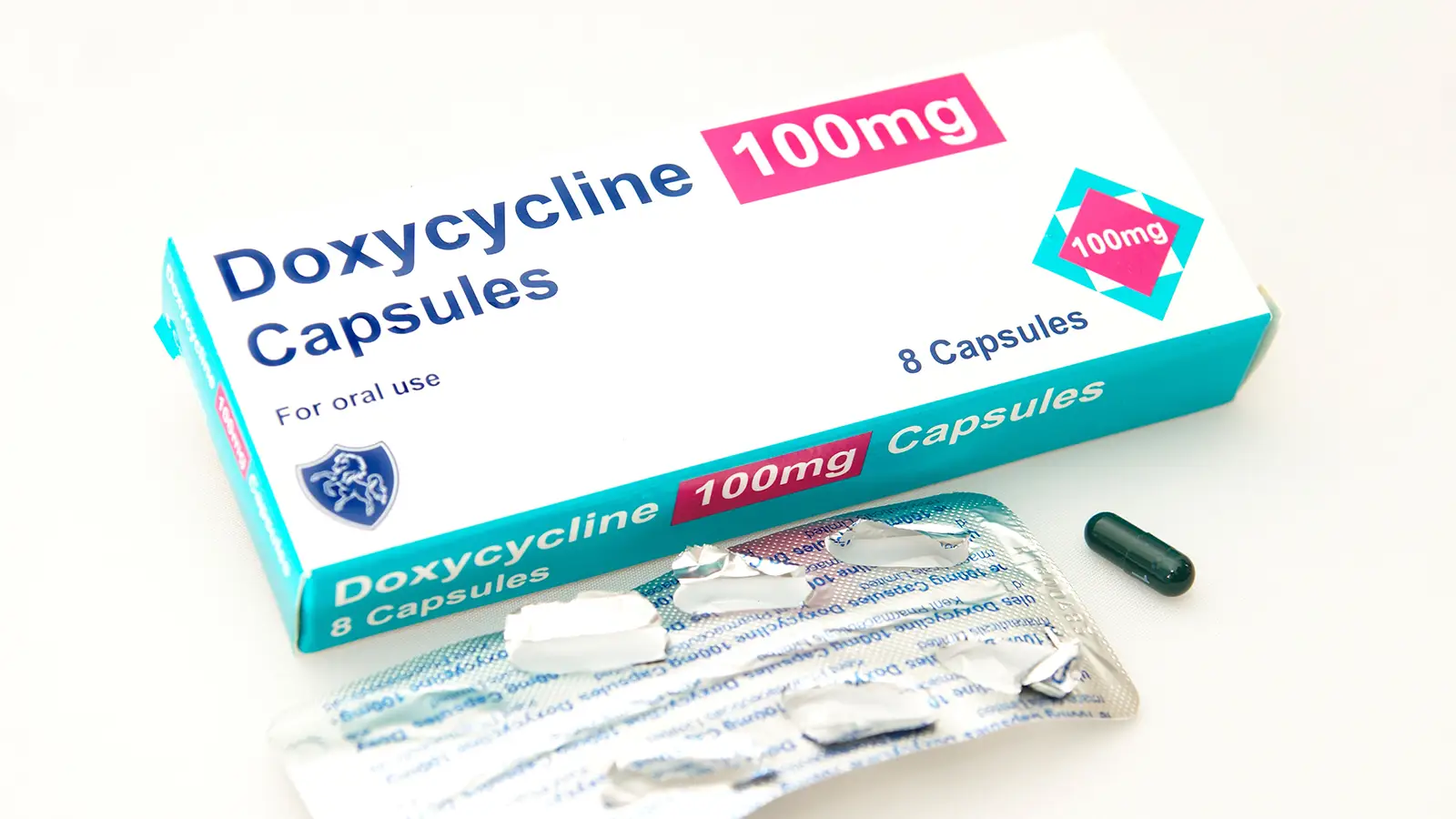 Box of Doxycycline 100 mg capsules with blister pack and single capsule placed beside it.