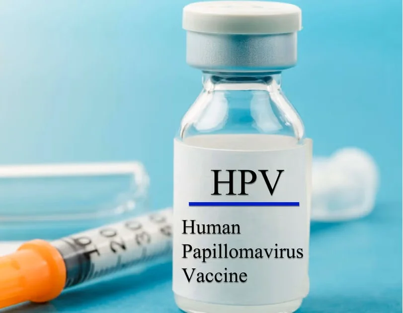 HPV vaccine vial with syringe on blue surface, representing immunisation against human papillomavirus.