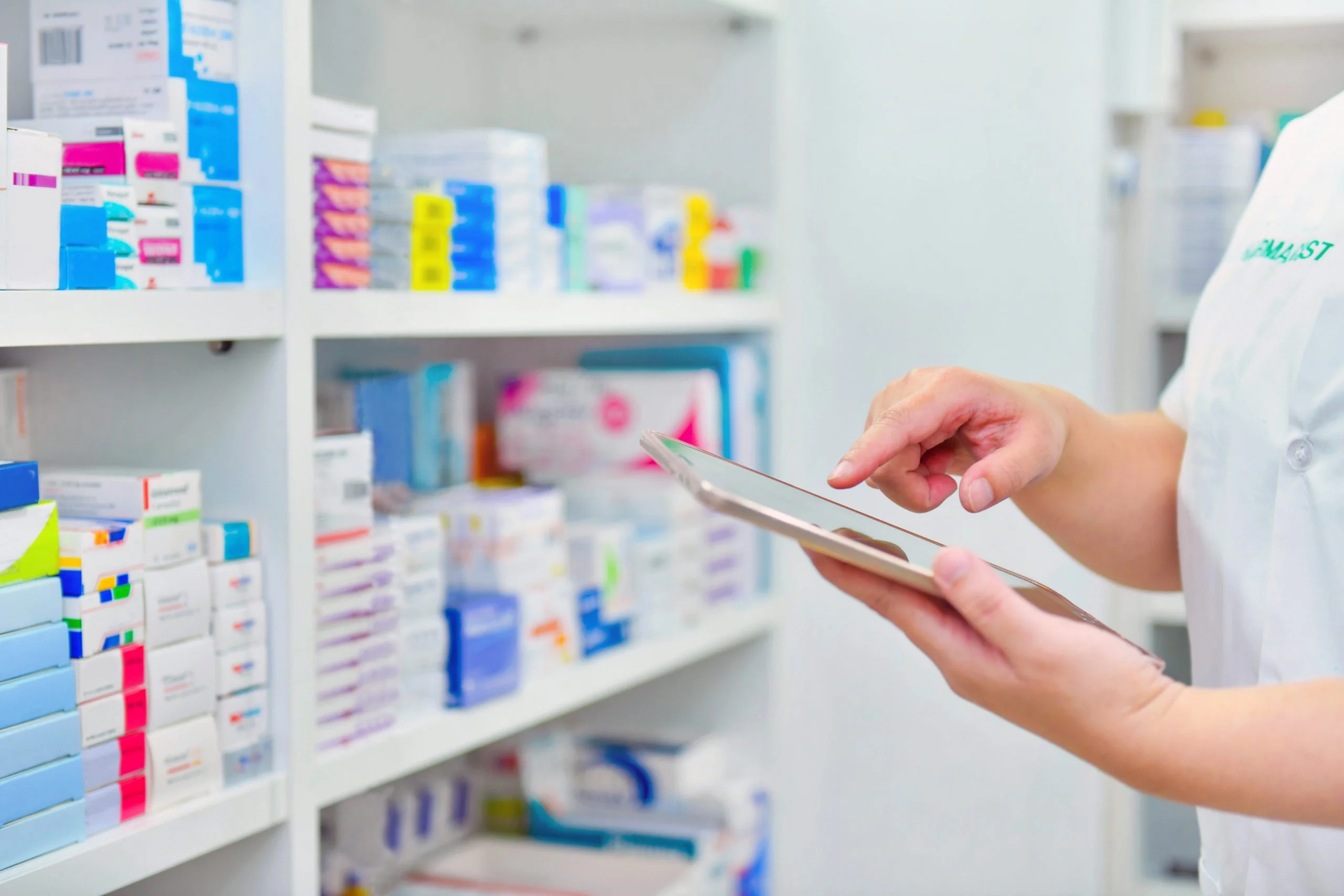 A pharmacist using tablet in front of medicine shelves at Yatton Pharmacy in Yatton, Bristol