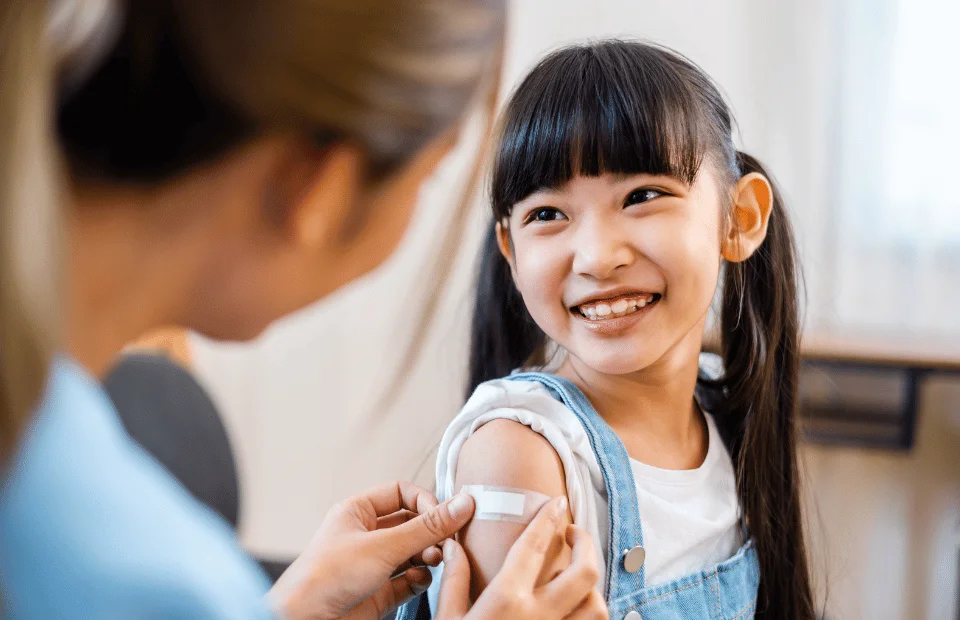 Child smiling after vaccination with bandage applied at Yatton Pharmacy in Yatton, Bristol