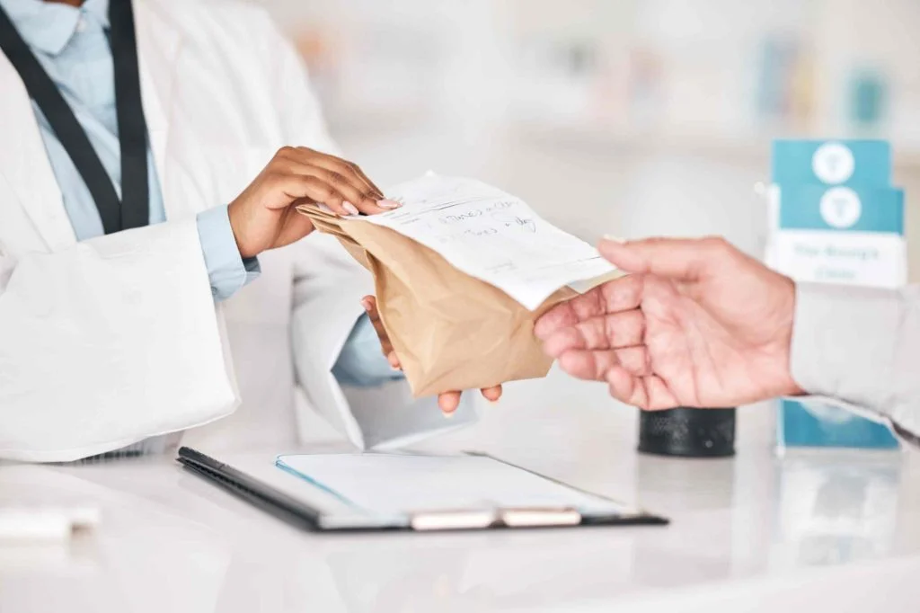 Pharmacist handing prescription bag to customer at Yatton Pharmacy in Yatton, Bristol