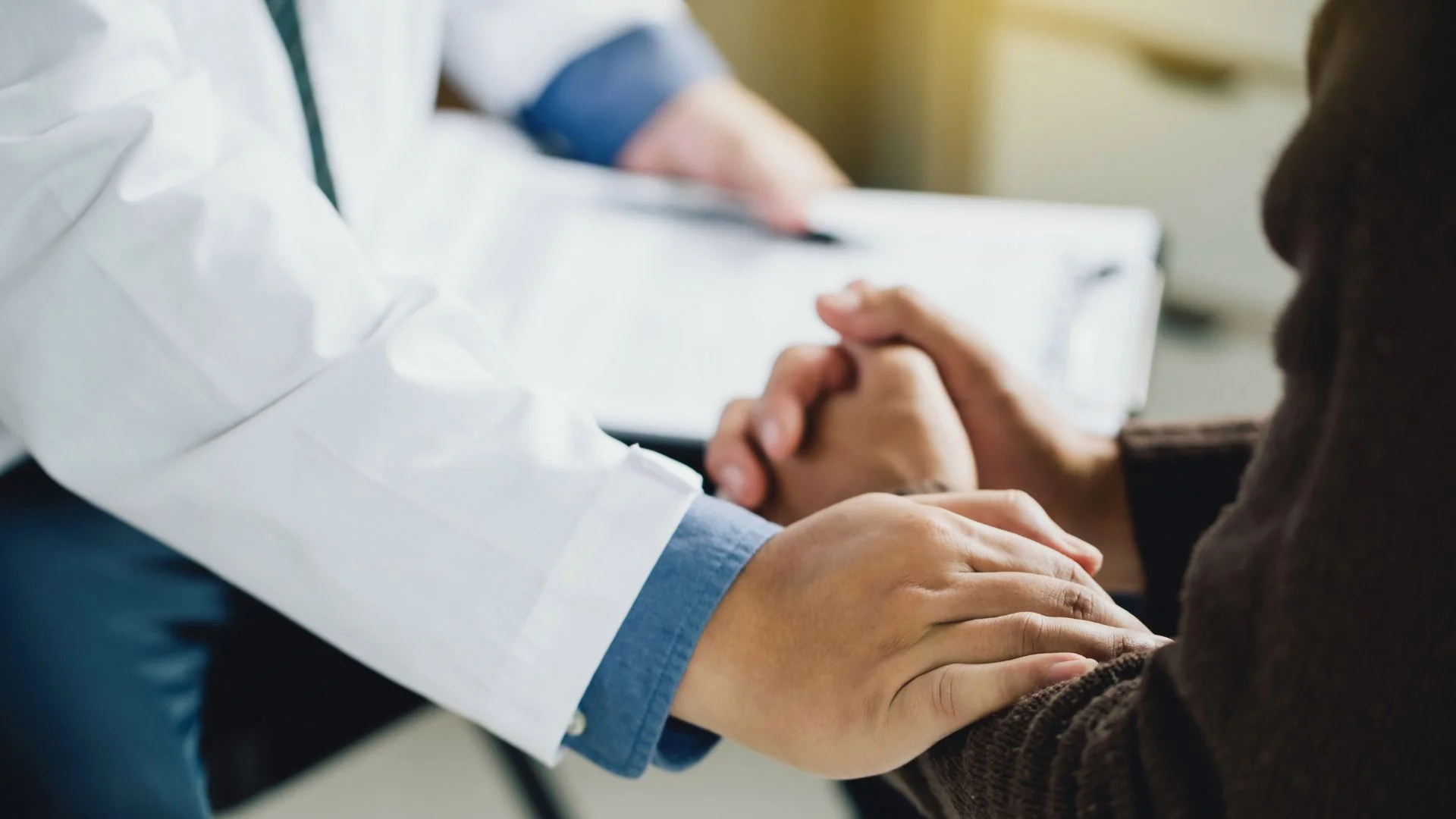 Doctor offering supportive hand to patient during consultation at Yatton Pharmacy in Yatton, Bristol