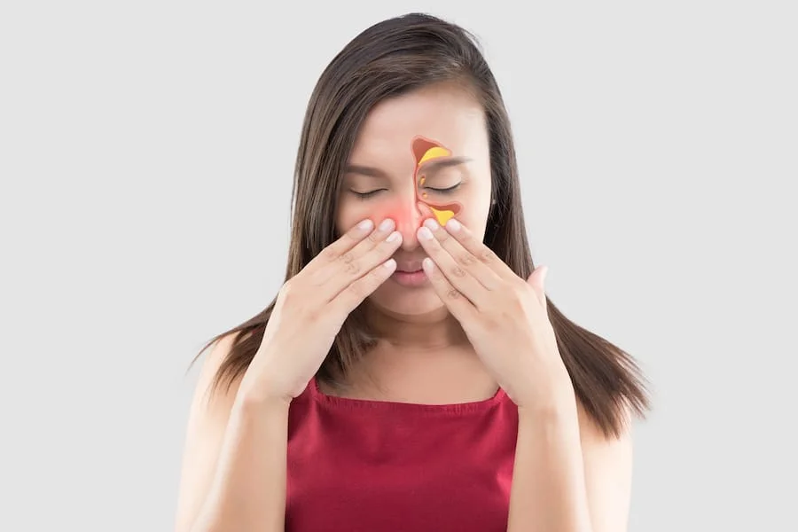 Person pressing nose with sinus cavities highlighted showing inflammation