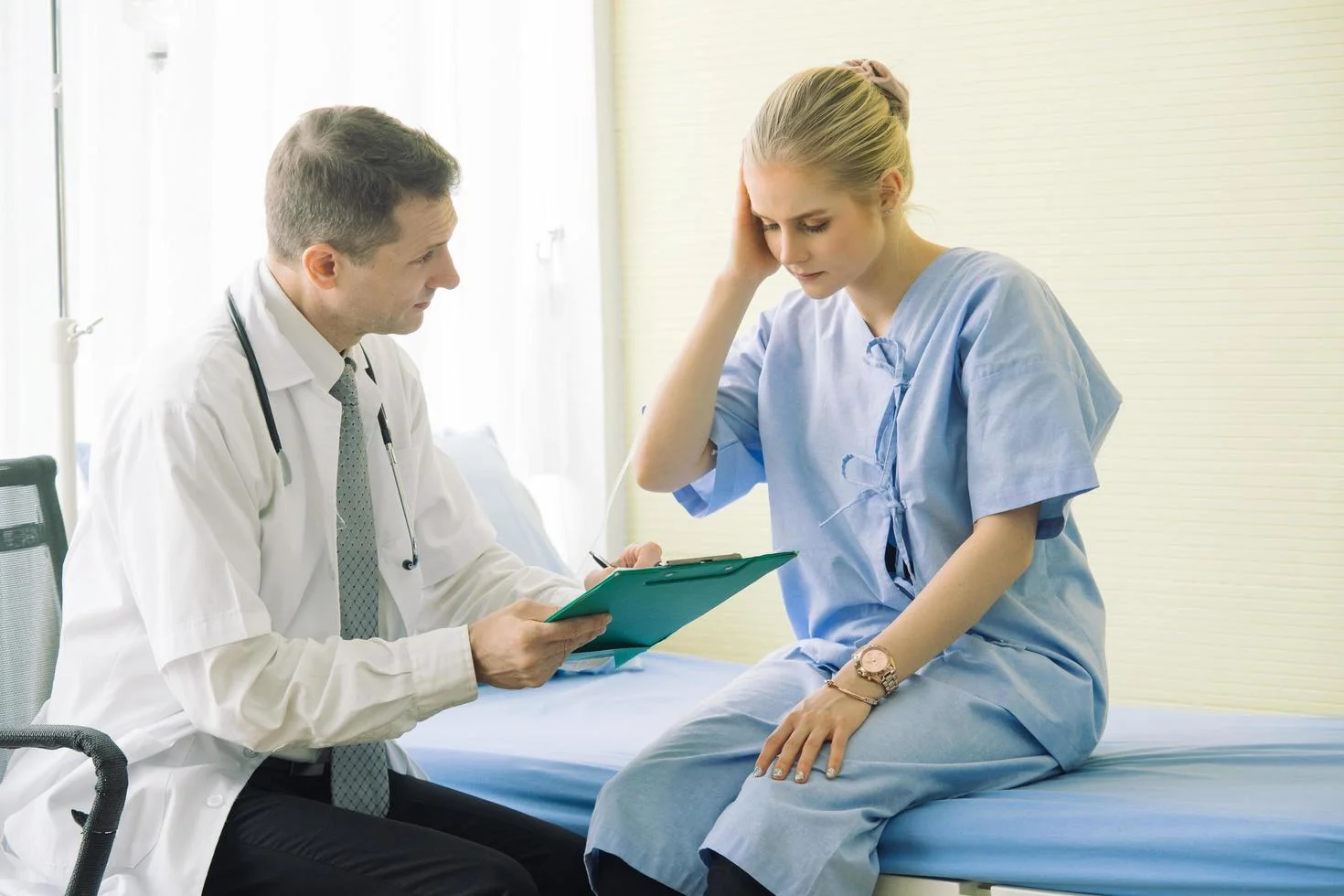 Doctor consulting patient with clipboard during examination at Yatton Pharmacy in Yatton, Bristol