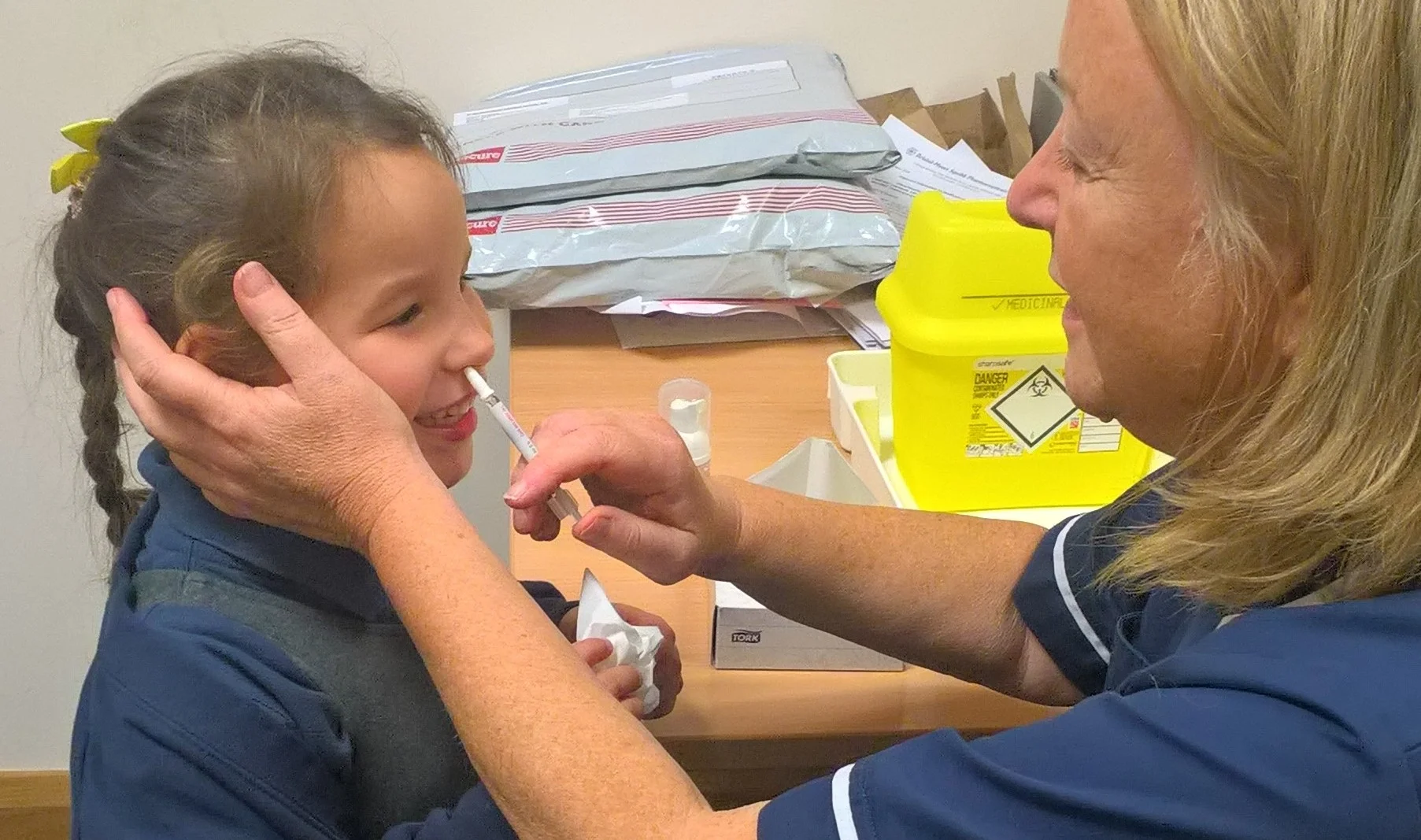 Healthcare professional administering nasal spray to child at Yatton Pharmacy in Yatton, Bristol