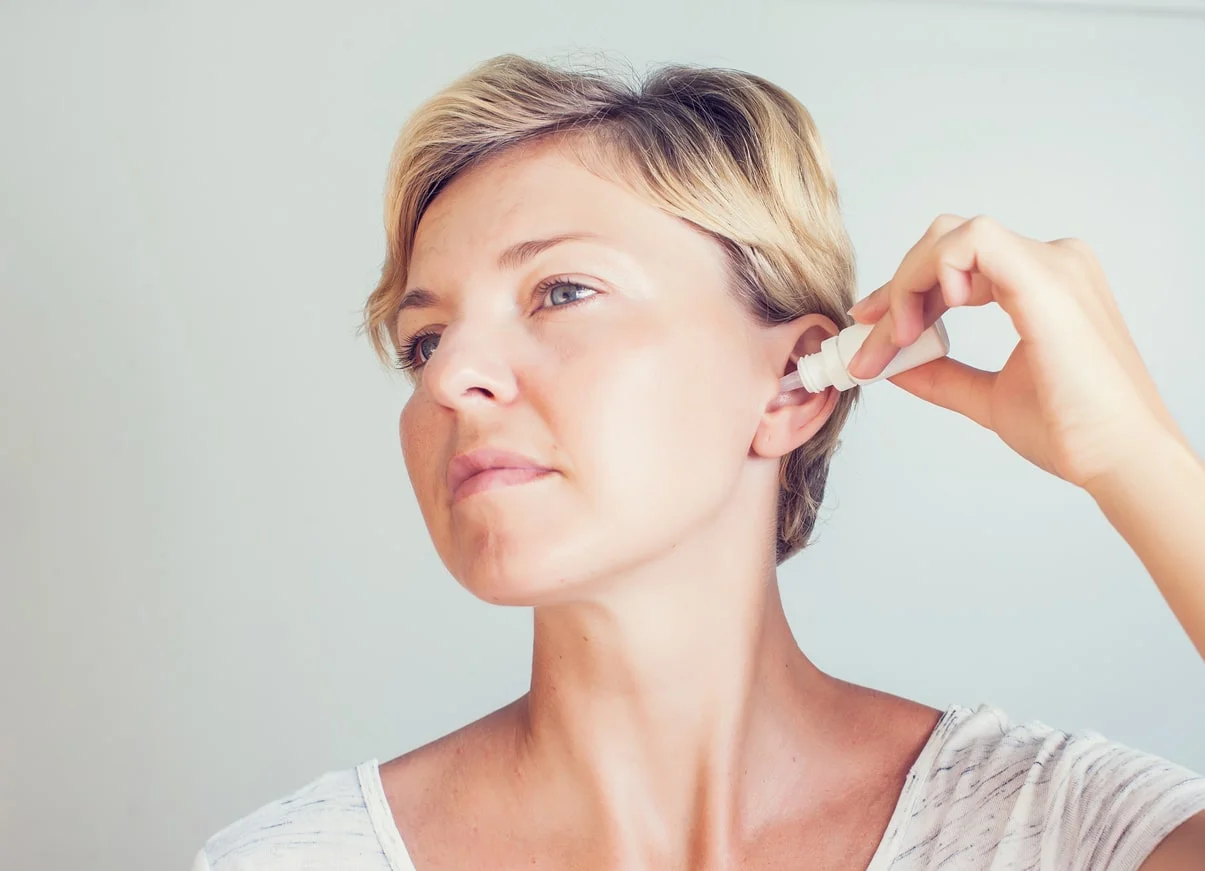Person applying ear drops with dropper at Yatton Pharmacy in Yatton, Bristol