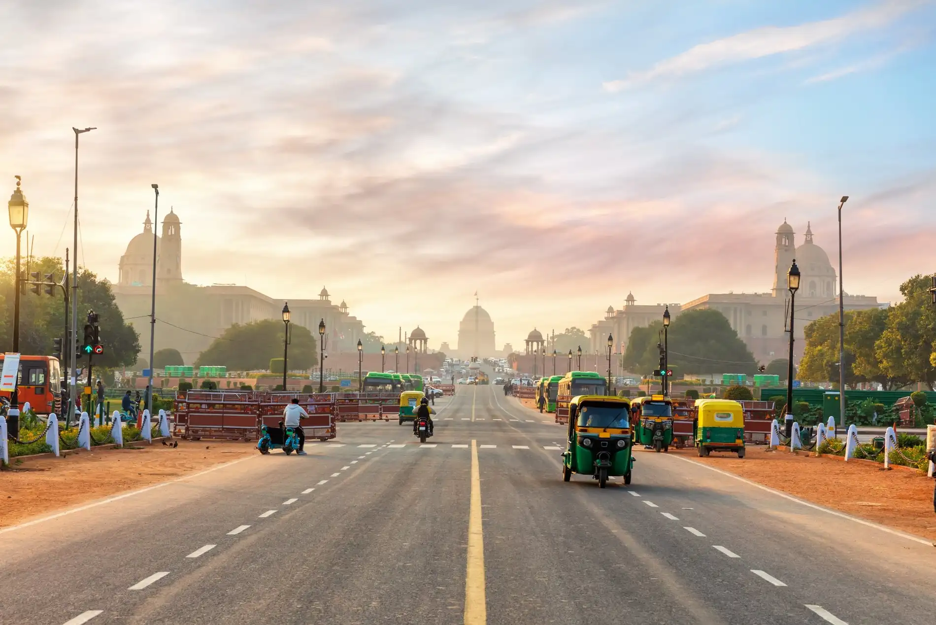 A wide avenue in New Delhi leads toward Rashtrapati Bhavan, lined with colonial-style buildings and busy traffic.